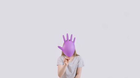 Young sad girl play with protective medical glove. Teenager with glove inflated like balloon. Quarantine, self isolation, depression, social distance, mental health concept. Stock photo.の写真素材