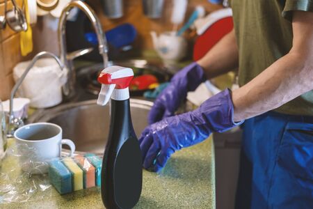 Man in protective mask and protective purple gloves does house cleaning during pandemic quarantine...