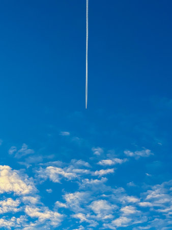 Airplane flying in the blue sky among sunset clouds.の写真素材