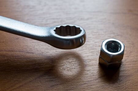 Metal wrench and nut on a wooden background.の写真素材