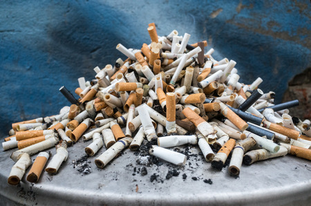 a mountain of cigarette butts in the trashcanの写真素材