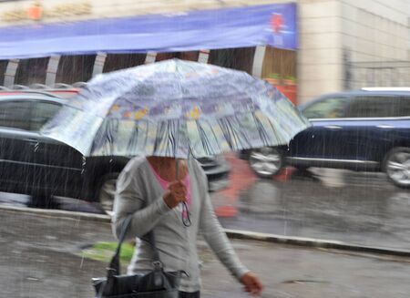 Lubricated image of a girl under an umbrella during a heavy rain outsideの写真素材