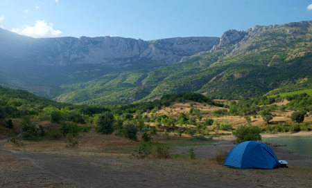 Blue tent on the shore of a mountain lakeの写真素材