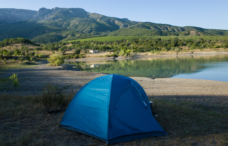 Blue tent on the shore of a mountain lakeの写真素材