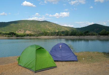 Blue and green tent on the shore of a mountain lakeの写真素材