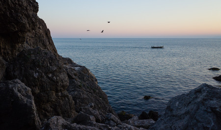 Tourist boat enters the Bay in the light of the setting sunの写真素材