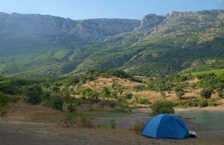 Blue tent on the shore of a mountain lakeの写真素材
