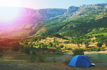 Blue tent on the shore of a mountain lakeの写真素材