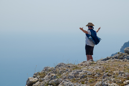 A young man in a cowboy hat is standing on the edge of the cliff with arms outstretchedのeditorial素材