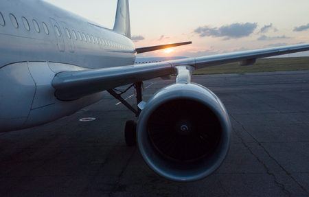 The wing and engine of the plane in the light of the setting sunの写真素材