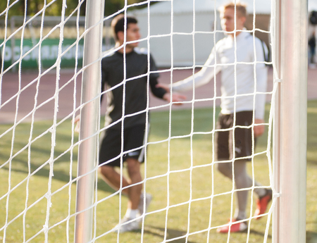 Blurred silhouettes of players shaking hands during a football match.の写真素材