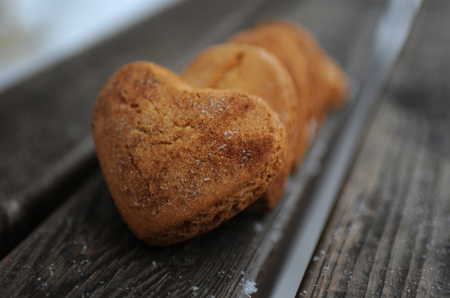 Homemade cookies with sugar and cinnamon in the form of hearts on a wooden backgroundの写真素材