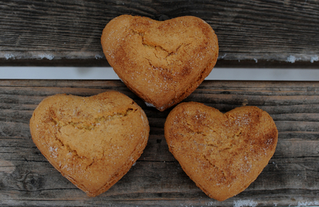 Homemade cookies with sugar and cinnamon in the form of hearts on a wooden background