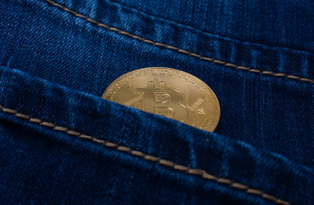 Bitcoin gold coin in the pocket of blue jeans.の写真素材