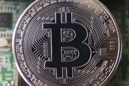 Silver souvenir coin Bitcoin on computer circuit board background.の写真素材