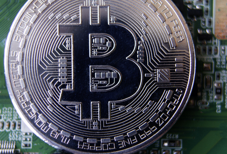 Silver souvenir coin Bitcoin on computer circuit board background.の写真素材