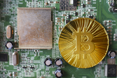 Gold souvenir coin Bitcoin on a computer circuit board background.の写真素材