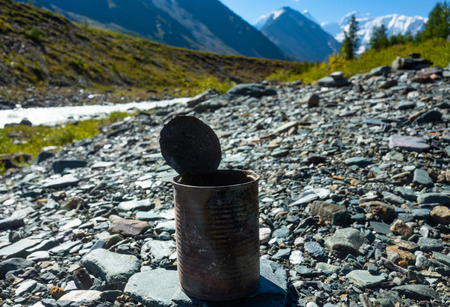 discarded can of canned food on the background of the mountain landscape