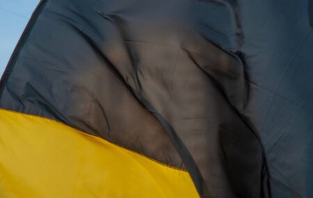 Yellow and black flag on the background of a multi-storey building