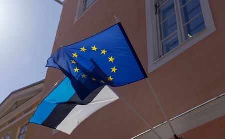Flags of Estonia and the European Union on the building against the blue sky on a bright Sunny day