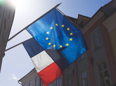 Flags of France and the European Union on the building against the blue sky on a bright Sunny day