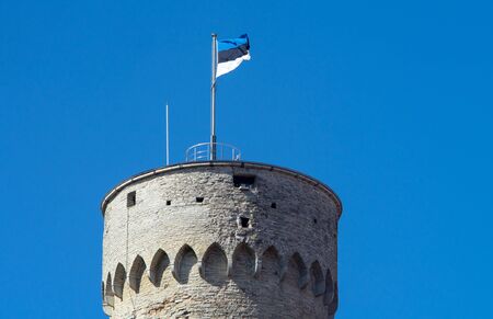 Estonian flag on the tower against the blue sky on a bright Sunny dayの写真素材