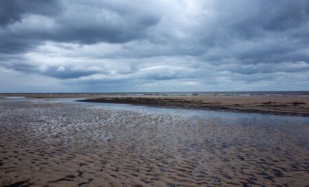 Reflection of clouds in a small lehman on the sandy shore of the Baltic Sea in Jurmala in cloudy...