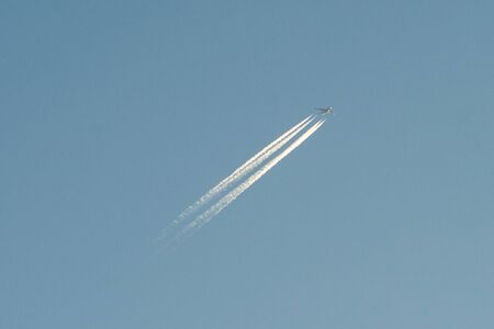 A plane with a reversible trail following it in the blue sky.