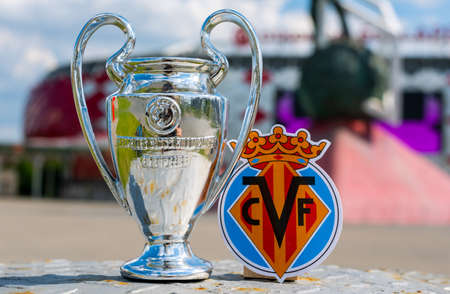 June 14, 2021 Villarreal, Spain. The emblem of the Villarreal CF football club and the UEFA Champions League Cup against the backdrop of a modern stadium.のeditorial素材