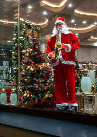 November 22, 2021, Moscow, Russia. Santa Claus is playing the saxophone in the window of a souvenir shop.のeditorial素材