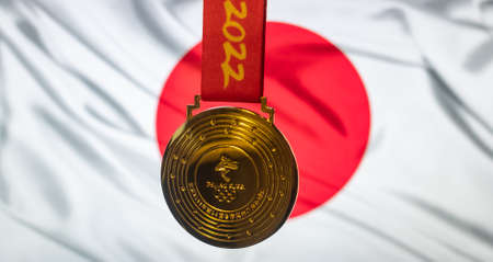 January 4, 2022, Beijing, China. Gold medal of the XXIV Olympic Winter Games against the background of the flag of Japan.のeditorial素材