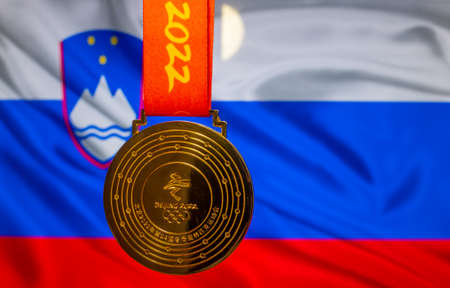 January 5, 2021, Beijing China. Gold medal of the XXIV Olympic Winter Games against the background of the flag of Slovenia.のeditorial素材