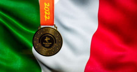 January 5, 2021, Beijing China. Gold medal of the XXIV Olympic Winter Games against the background of the flag of Italy.のeditorial素材