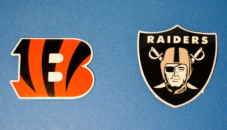 January 14, 2022 Cincinnati, Ohio. The emblems of the football clubs of the playoffs of the National Football League season 2021/2022 Cincinnati Bengals and Las Vegas Raiders on a blue background.のeditorial素材