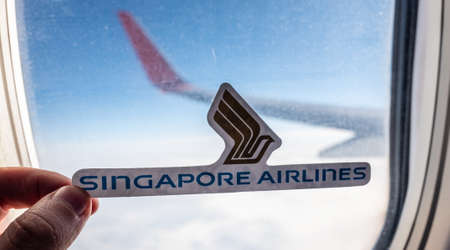 December 6, 2021 Singapore. The emblem of Singapore Airlines against the backdrop of an airplane window.のeditorial素材