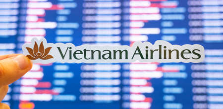 December 11, 2021, Hanoi, Vietnam. The emblem of Vietnam Airlines against the background of an electronic board with flight schedules at the international airport.のeditorial素材
