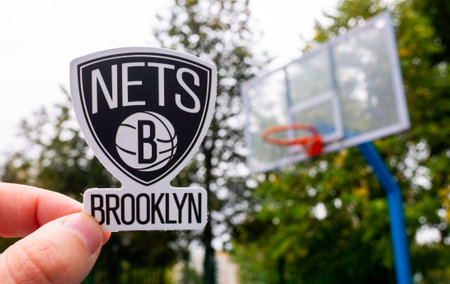 September 15, 2021, New York, USA, A man holds the logo of the Brooklyn Nets basketball club in his hand on the sports ground.のeditorial素材