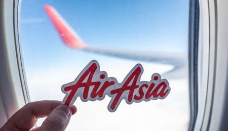 December 6, 2021, Kuala Lumpur, Malaysia. The emblem of the airline AirAsia on the background of the window of the aircraft.のeditorial素材