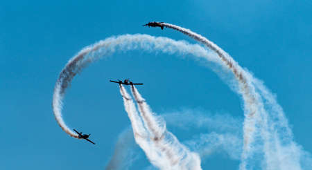 Silhouettes of training aircraft performing aerobatics on a clear sunny day.の写真素材