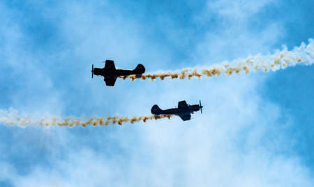 Silhouettes of training aircraft performing aerobatics on a clear sunny day.