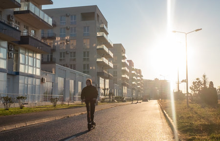 December 10, 2021, Sochi, Russia. A man rides an electric scooter in the Imereti quarter in Adler in the rays of the rising sun.のeditorial素材