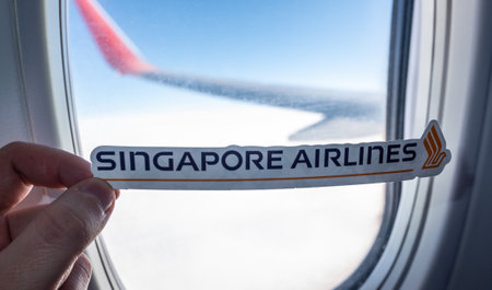December 6, 2021 Singapore. The emblem of Singapore Airlines against the backdrop of an airplane window.のeditorial素材