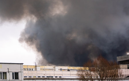 A cloud of black smoke from a fire in a building materials warehouse.