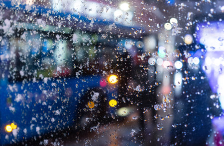 Snow-covered glass of a bus stop on a winter evening. blurred imageの写真素材