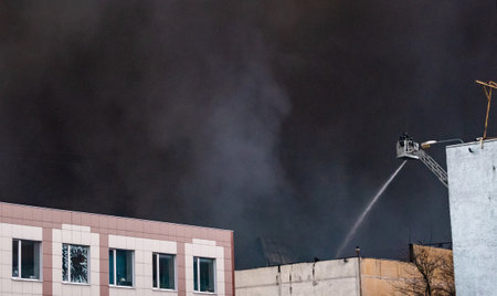 The fire brigade, standing on the fire escape, extinguishes a fire in an industrial building with a...