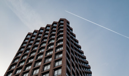 A trace of a passing plane over a modern multi-storey business class building.