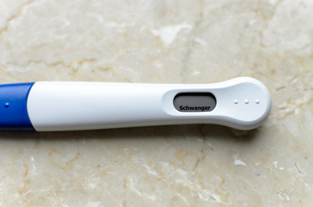 Positive pregnancy test, white-blue test device on a marble background