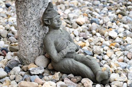 Stone garden gnome at the lunch break before the background of stonesの写真素材