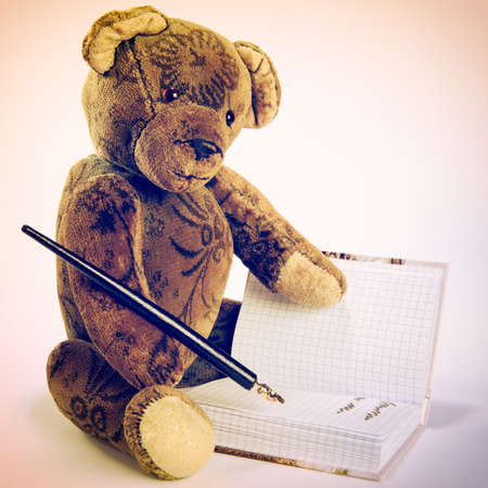 Antique Teddy writes with a fountain pen in a bookの写真素材