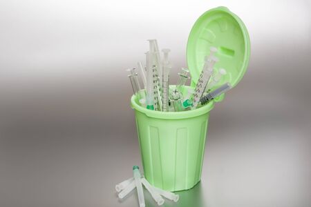Green Garbage can with medical waste. Syringes protrude out of it.の写真素材